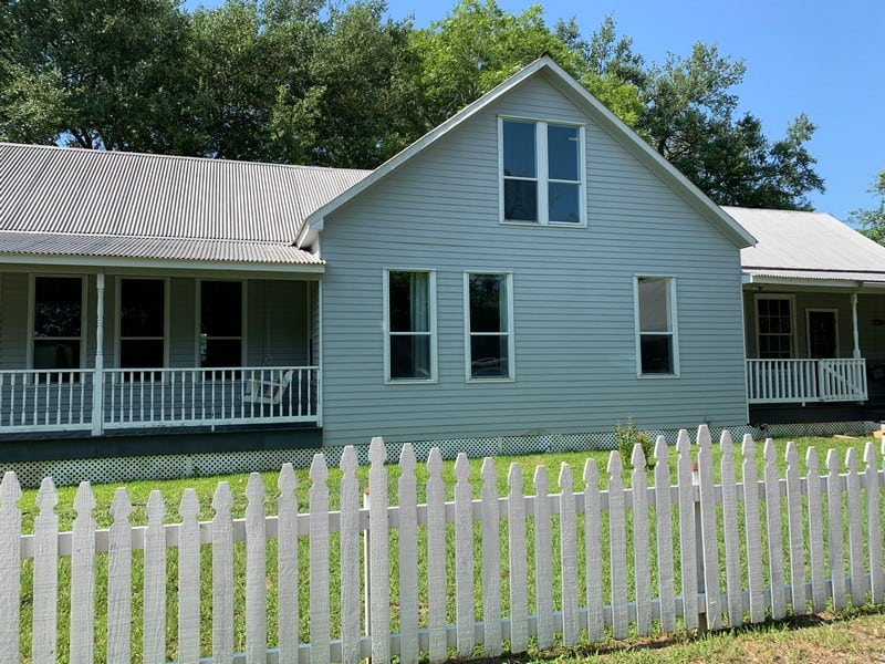 White house with porch and picket fence.