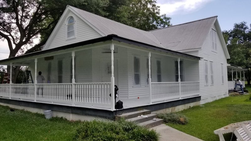 Beautiful white house with large porch and trees.